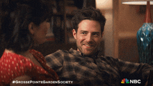 a man and a woman are sitting on a couch and the nbc logo is visible