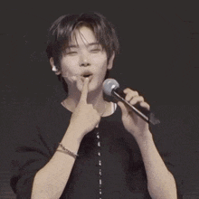 a young man is singing into a microphone while wearing ear buds .