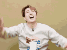 a man wearing a sweater with a picture of a hamburger on it laughs with his arms outstretched