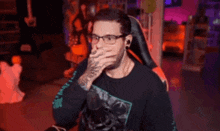 a man wearing glasses and ear plugs is yawning in front of a microphone .
