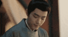 a man in a kimono is smiling with his eyes closed and looking down .