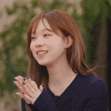 a woman in a blue sweater is clapping her hands and smiling