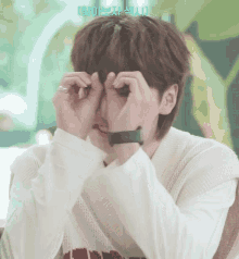 a man wearing a watch and a ring covering his eyes