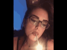 a woman with glasses is smoking a cigarette with a lighter in her mouth .