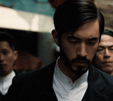 a man with a beard is wearing a black suit and a white shirt