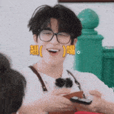 a young man wearing glasses is holding a cell phone
