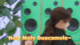 a woman standing in front of green speakers with the words holy moly guacamole written on it