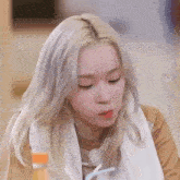 a woman with blonde hair is sitting at a table with a glass of orange juice in her hand .