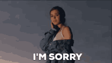 a woman in a denim jacket is standing in front of a cloudy sky and saying i 'm sorry .