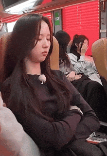 a woman sleeping on a bus with her eyes closed and a phone in her hand
