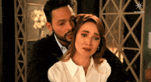 a man is hugging a woman who is crying in front of a sign that says " las estrellas "