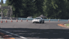 a white race car is driving on a track with cones