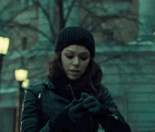 a woman wearing a black beanie is looking at a cell phone