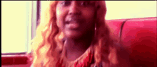 a woman with long red hair is sitting in a red chair talking on a cell phone .
