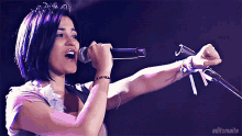 a woman singing into a microphone with editsmaite written on the bottom right