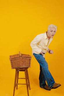 a man stands next to a wicker basket on a stool
