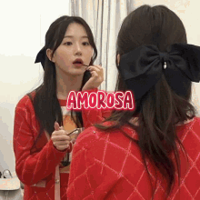 a woman is applying lipstick in front of a mirror and the word amorosa is above her head