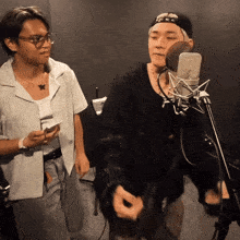 a man singing into a microphone while another man stands behind him