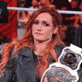 a woman with red hair is holding a championship belt and making a sad face