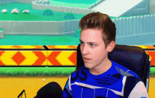 a young man is sitting in front of a microphone wearing a blue adidas shirt .