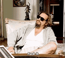 a man wearing sunglasses is sitting in a chair saying fuck it