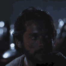 a man with a beard is looking at the camera in the dark
