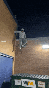 a person is jumping over a dumpster with a wm logo on it