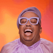 a man wearing glasses and a purple hat is laughing with his mouth open