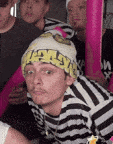 a man wearing a striped shirt and a beanie that says " nasty "