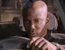a man with vitiligo is driving a car and looking at the camera .