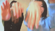 two women are making a heart shape with their hands while standing next to each other .