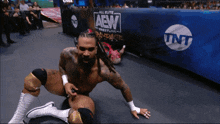 a wrestler is kneeling down in front of a banner that says aew wrestling