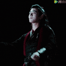 a man with long hair is singing into a microphone in a dark room ..
