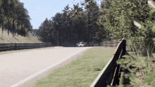 a race car is driving down a track with trees on the side