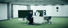 a man sits at a desk in an office talking on the phone