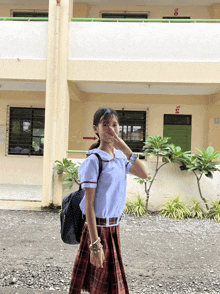 a girl in a school uniform covering her face in front of a building that has the number 10 on it