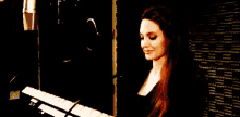 a woman is singing into a microphone while playing a piano