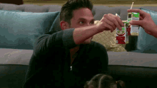 a man is sitting on a couch drinking from a carton that says ' juice ' on it
