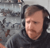 a man wearing headphones is standing in front of a glass display case with dragon figurines on it .