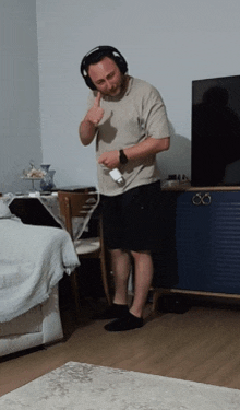 a man wearing headphones stands in front of a television