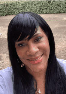 a woman wearing a white shirt and a necklace smiles for the camera