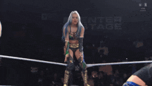 a woman in a wrestling ring with a sign that says enter stage in the background