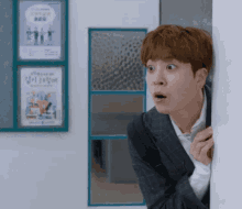 a man in a suit is peeking over a wall and making a surprised face