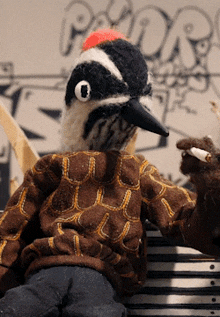 a stuffed bird wearing a giraffe sweater is sitting in front of a sign that says padre