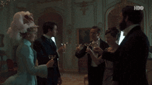 a group of people toasting in a room with hbo on the bottom