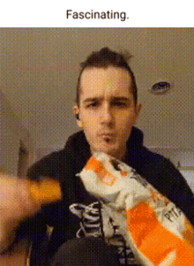 a man in a black hoodie is eating a bag of chips .