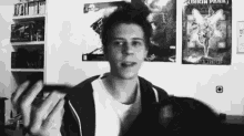a black and white photo of a young man standing in front of a linkin park poster .