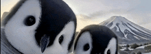 two penguins are standing next to each other in front of a snowy mountain