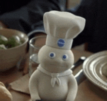 a pillsbury dough boy is sitting on a table with plates and bowls