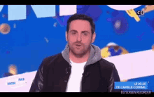 a man in a black jacket is standing in front of a blue background